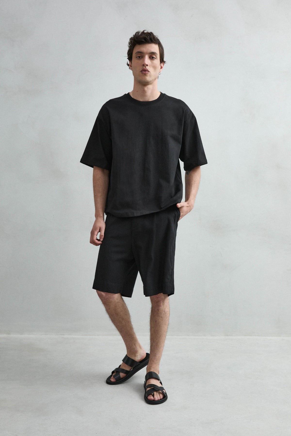 Camiseta cropped oversize negra lisa de hombre, vista de cuerpo entero.