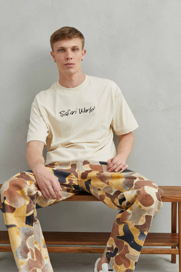 Vista frontal de camiseta beige oversize unisex con jirafa estampada - Safari World