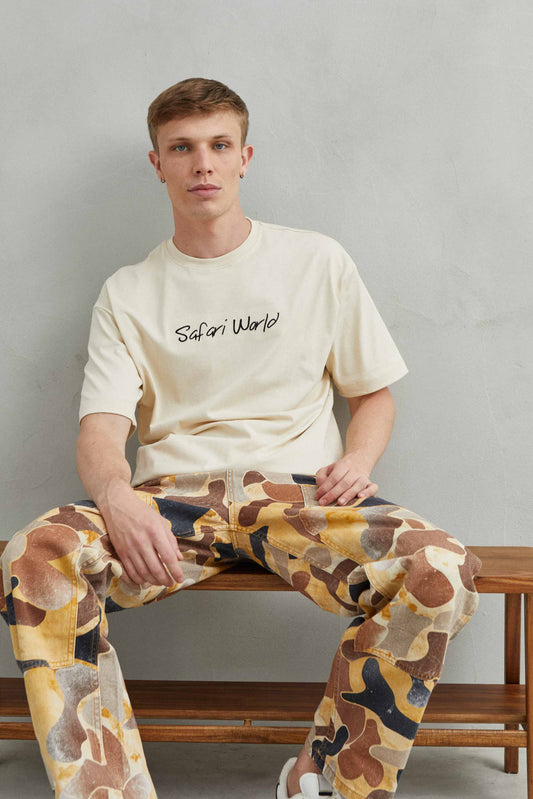 Vista frontal de camiseta beige oversize unisex con jirafa estampada - Safari World