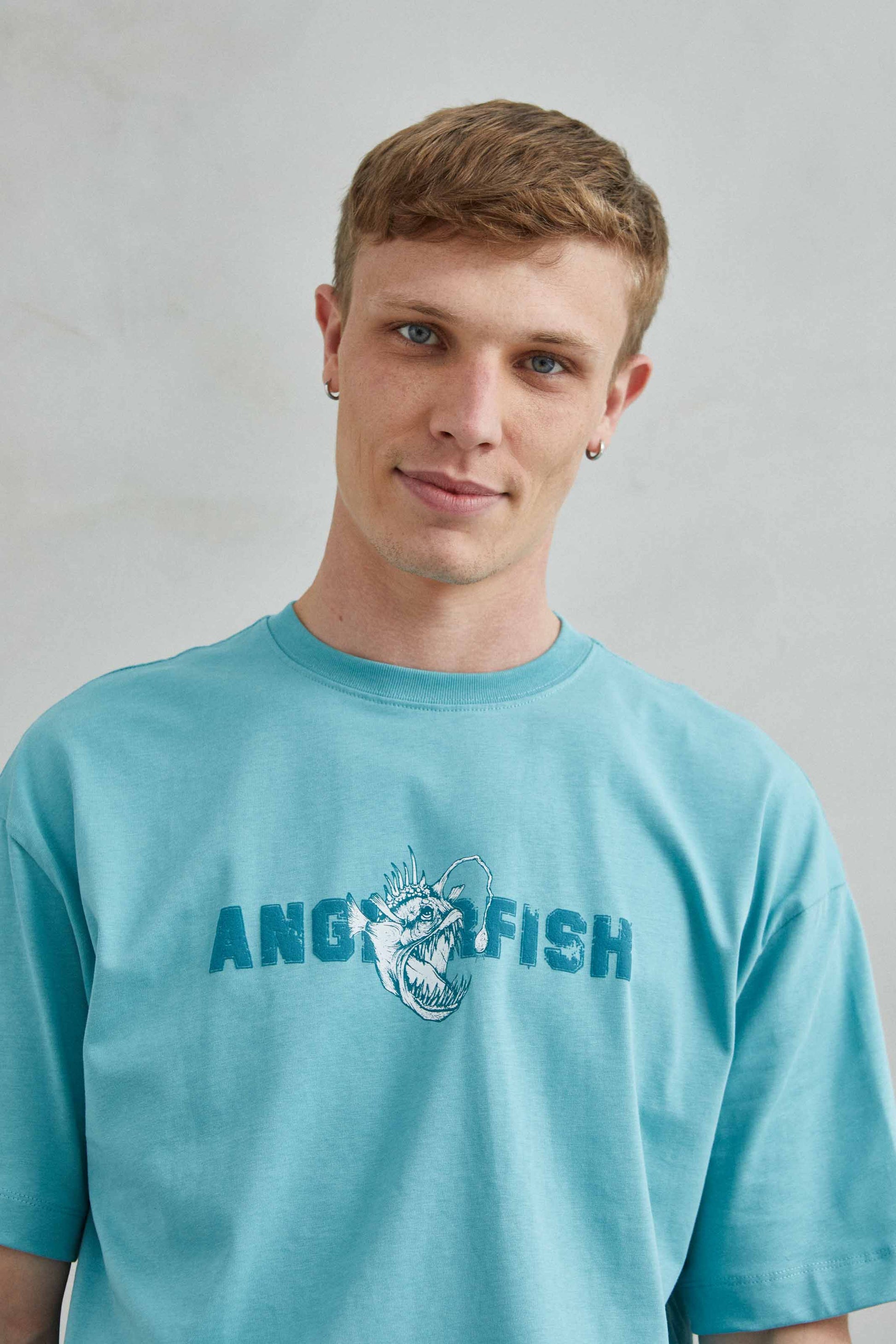 Modelo llevando camiseta oversize con diseño de rape y piraña, estilo streetwear unisex