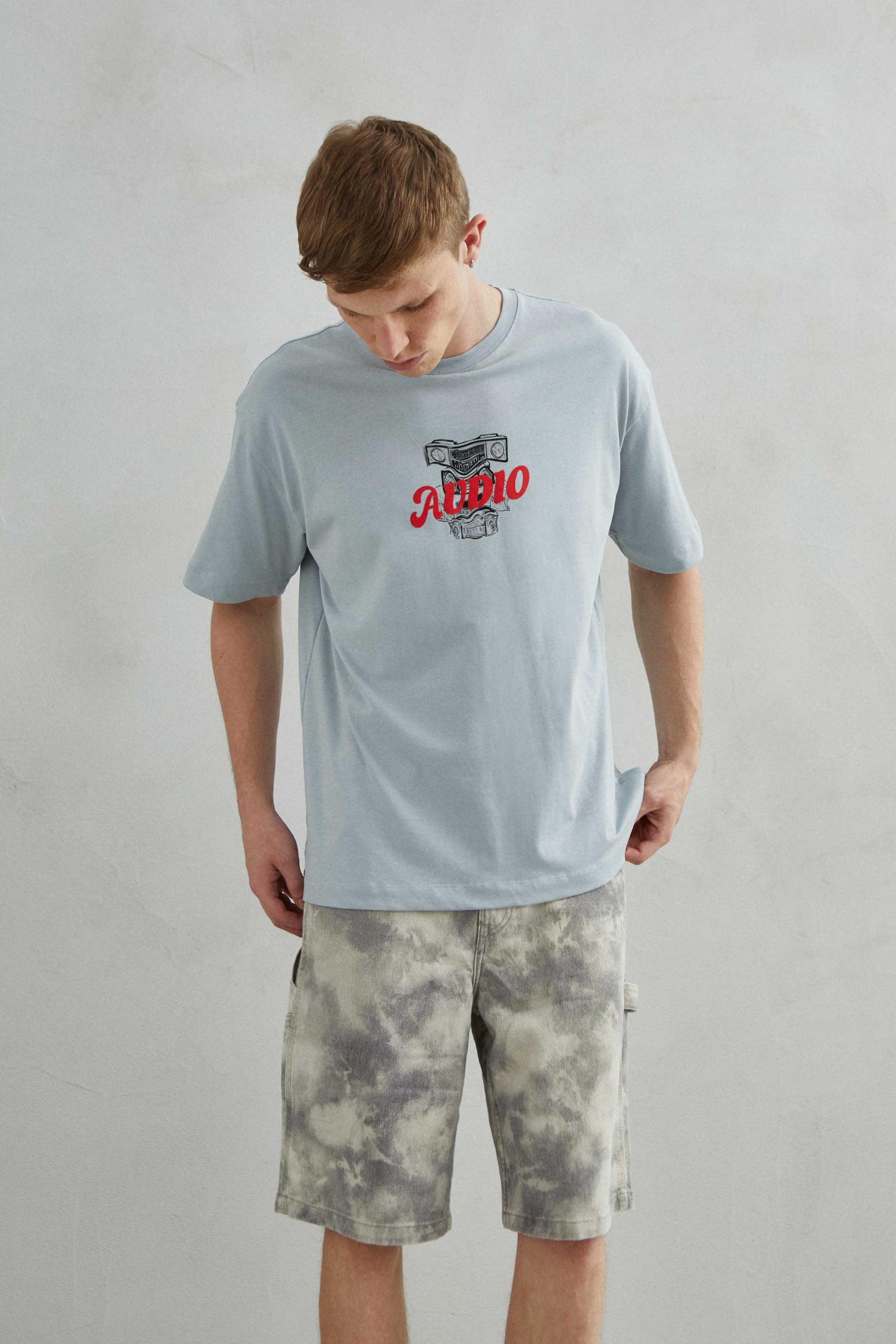 Primer plano del diseño "AUDIO" en la camiseta gris.