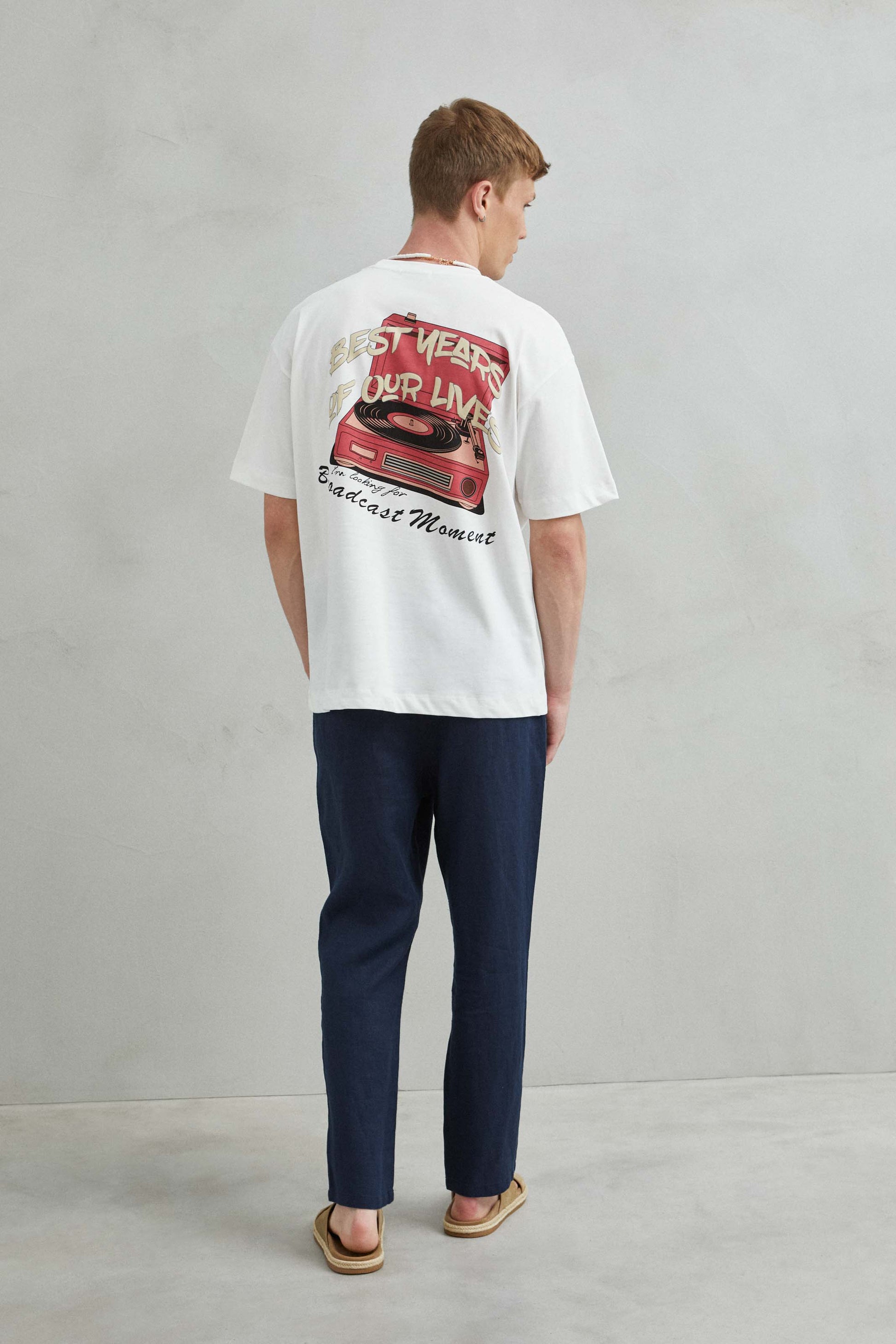 Modelo masculino con camiseta oversize blanca "Boadcast", estilo urbano.