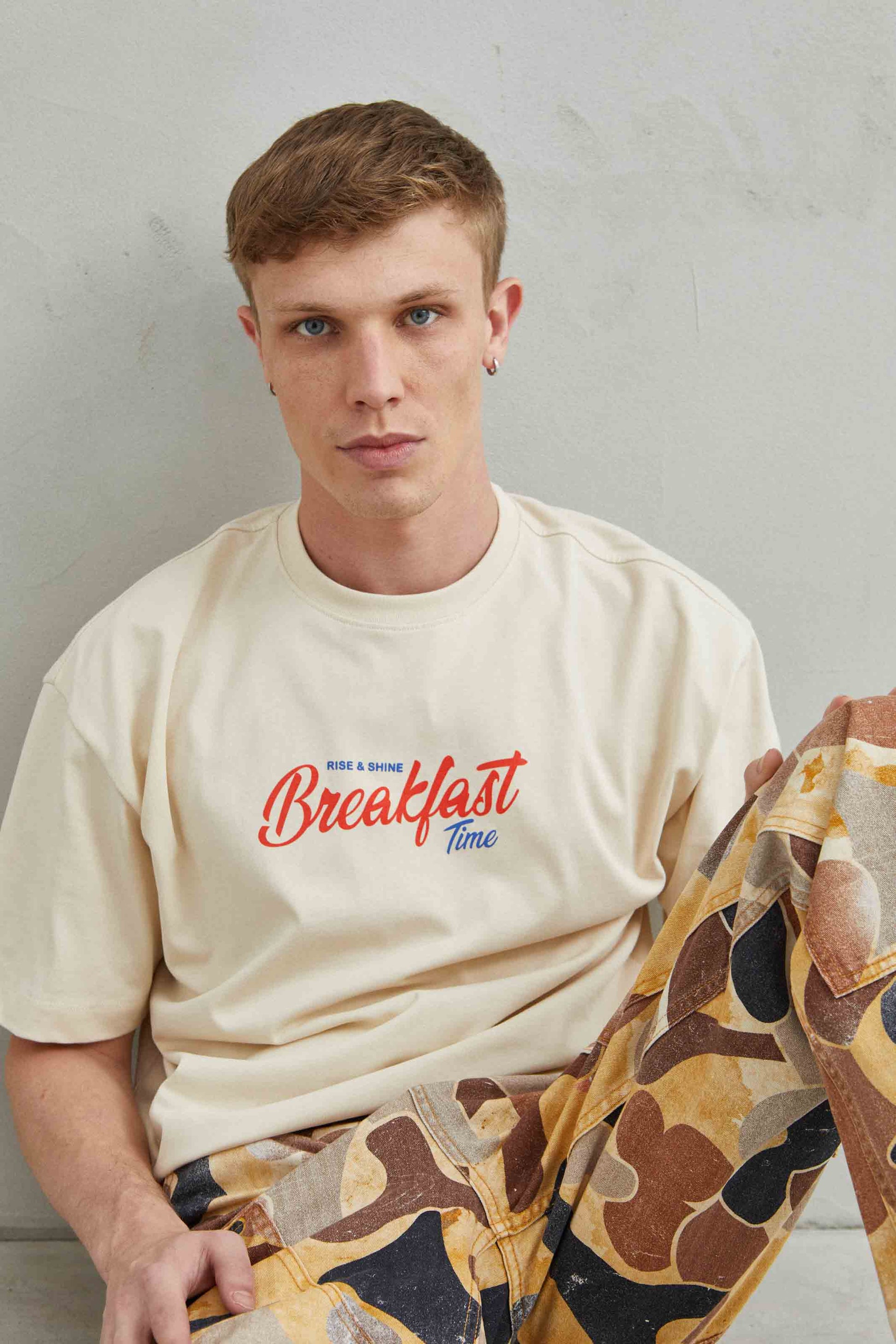 Camiseta oversize unisex beige con diseño gráfico "Breakfast y Croissant" en el pecho.