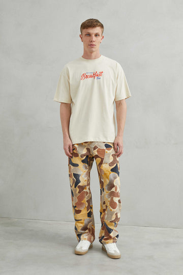  Primer plano del diseño "Breakfast y Croissant" en la camiseta beige.