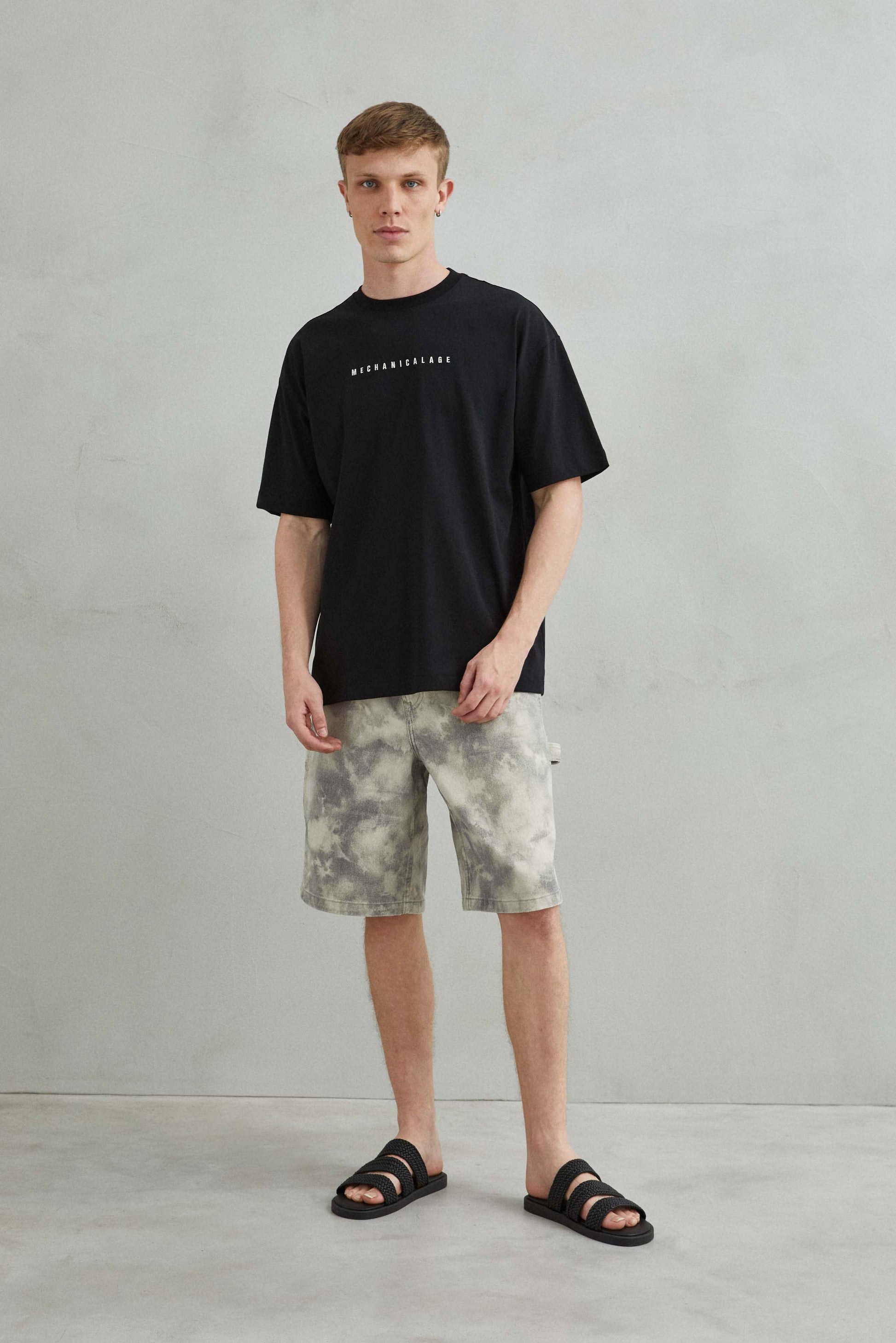 Modelo masculino con camiseta oversize negra "Futurism", estilo urbano.