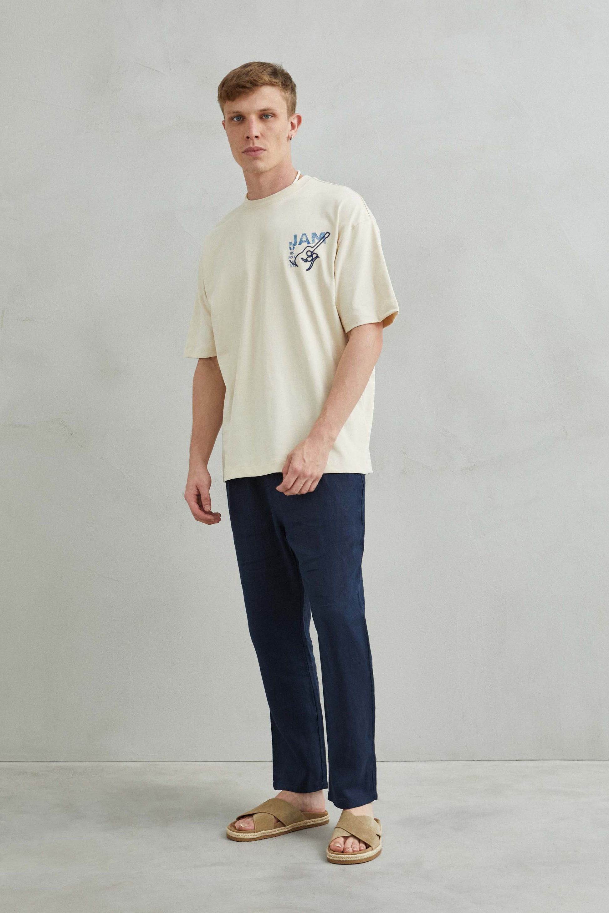Modelo usando camiseta beis de algodón con diseño musical de guitarras