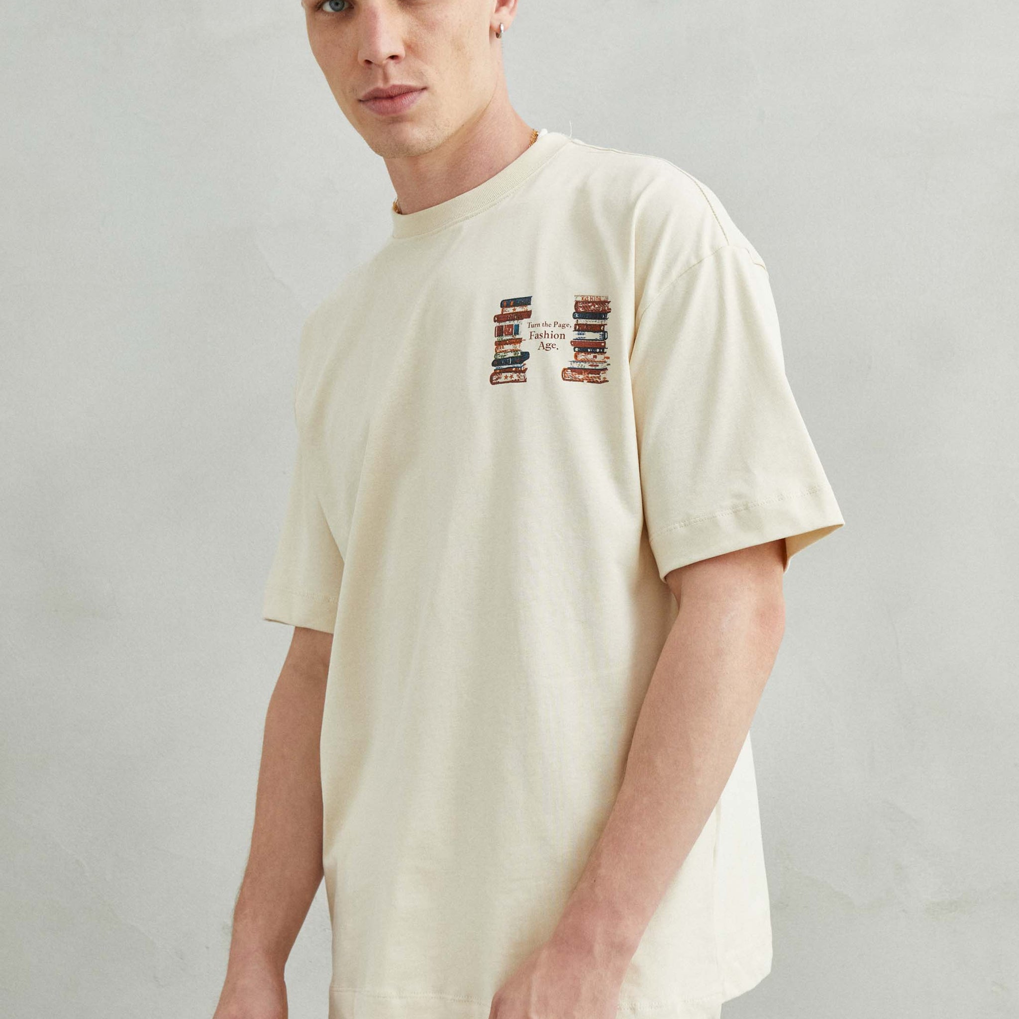 Camiseta beige oversize unisex con diseño TURN THE PAGE, FASHION AGE y libros