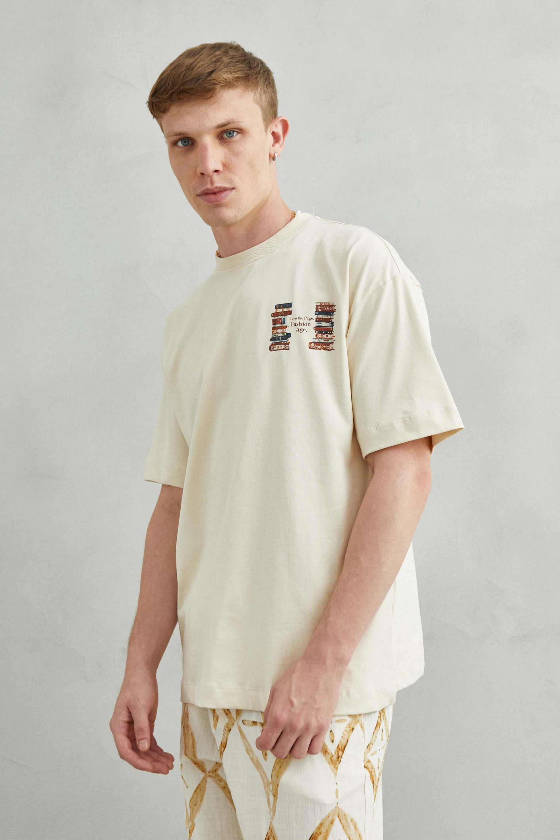 Camiseta beige oversize unisex con diseño TURN THE PAGE, FASHION AGE y libros