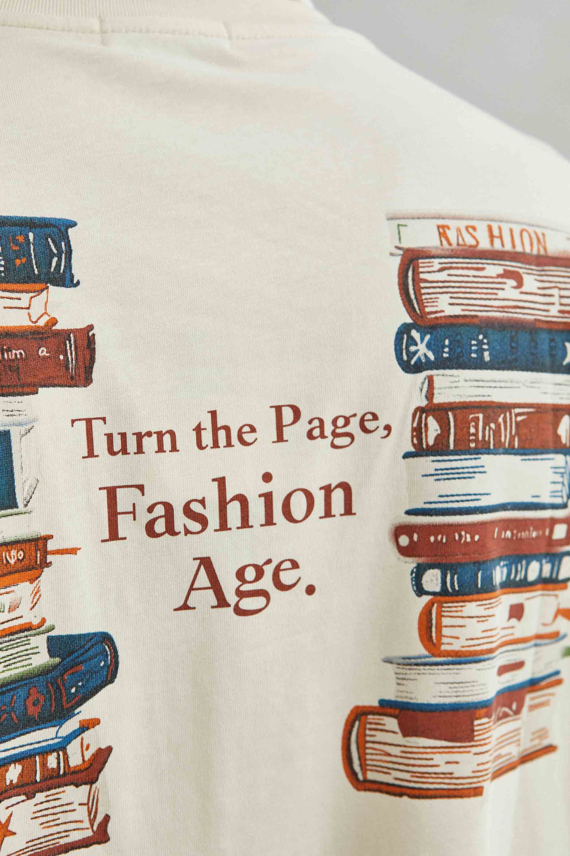 Camiseta 100% algodón con diseño de libros y mensaje TURN THE PAGE, FASHION AGE