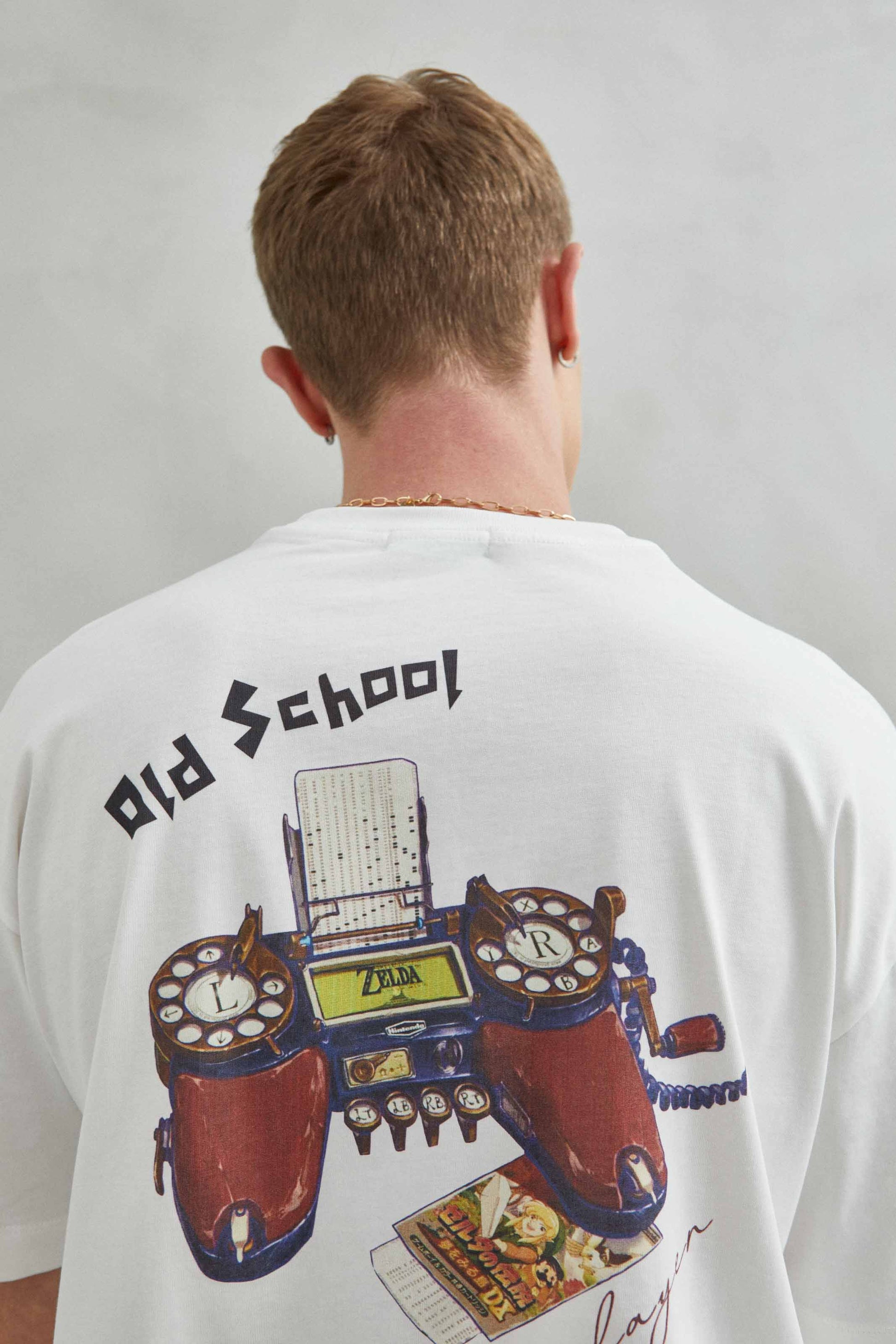 Modelo con camiseta blanca oversize unisex, estilo Old School con consola retro de videojuegos y diseño vintage.