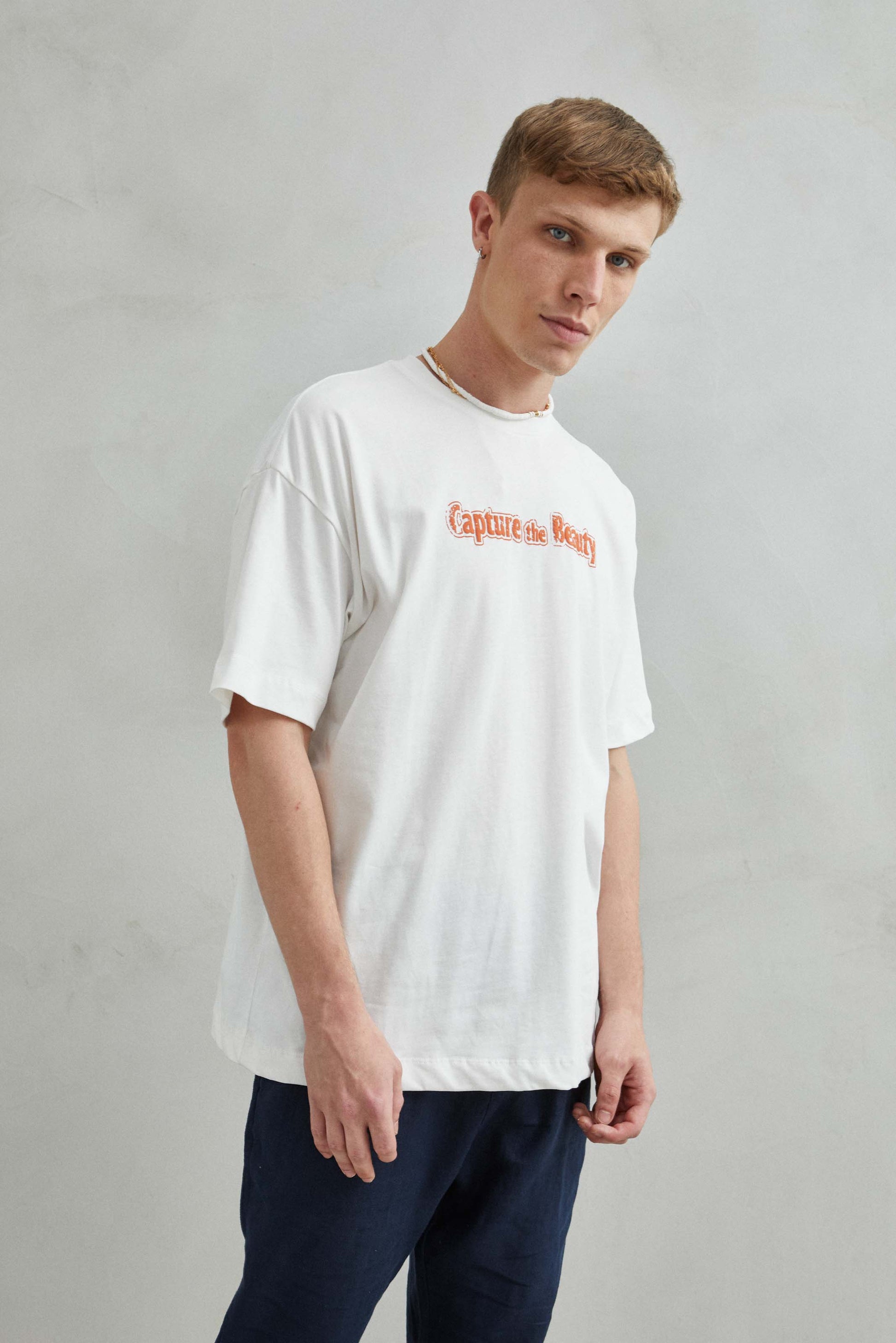 Vista del diseño de paisaje con montañas, árboles y mar en la camiseta blanca oversize unisex.