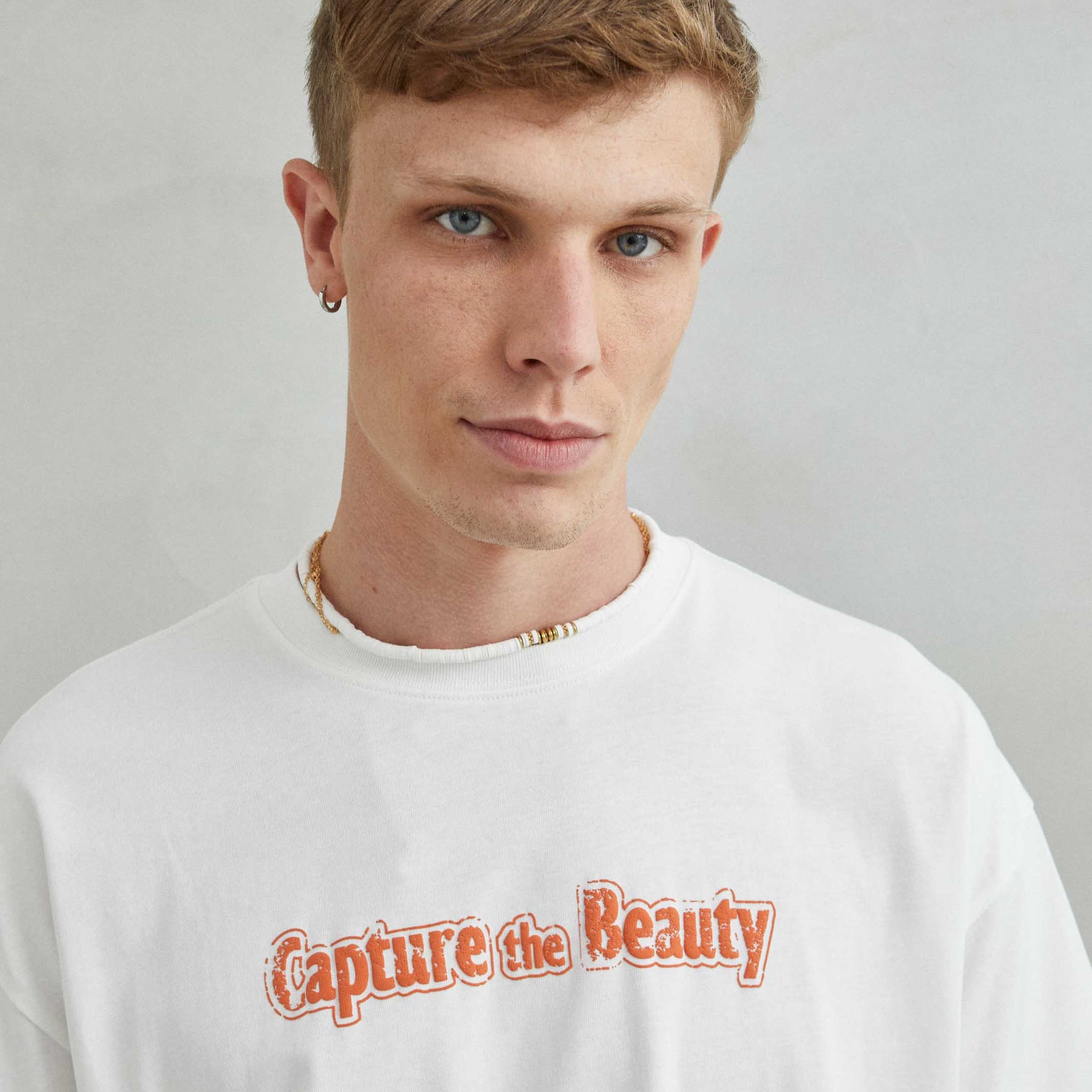 Camiseta blanca oversize unisex con diseño "CAPTURE THE BEAUTY", frente con textura de espuma y diseño natural
