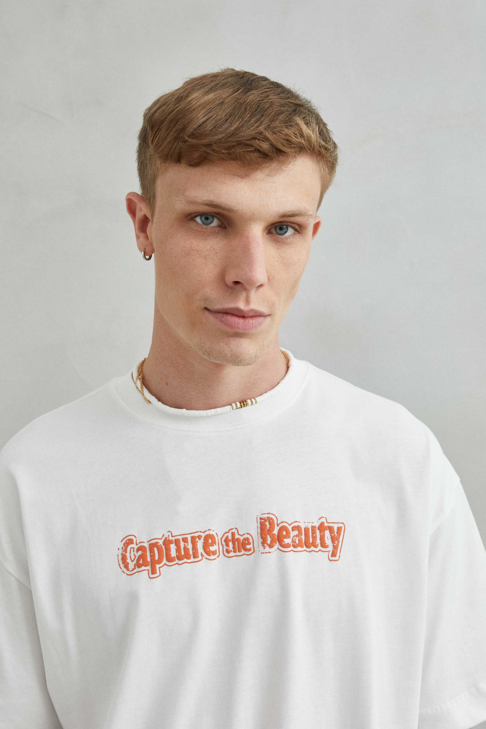 Camiseta blanca oversize unisex con diseño "CAPTURE THE BEAUTY", frente con textura de espuma y diseño natural