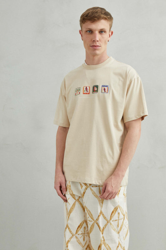  Camiseta beige oversize unisex con diseño en relieve de loro, palmera y frutas tropicales como maracuyá y pitaya.