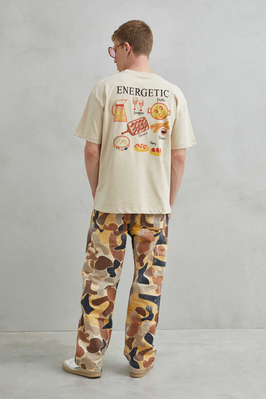 Vista frontal de camiseta beige oversize unisex con diseño de tapas, churros y gastronomía española