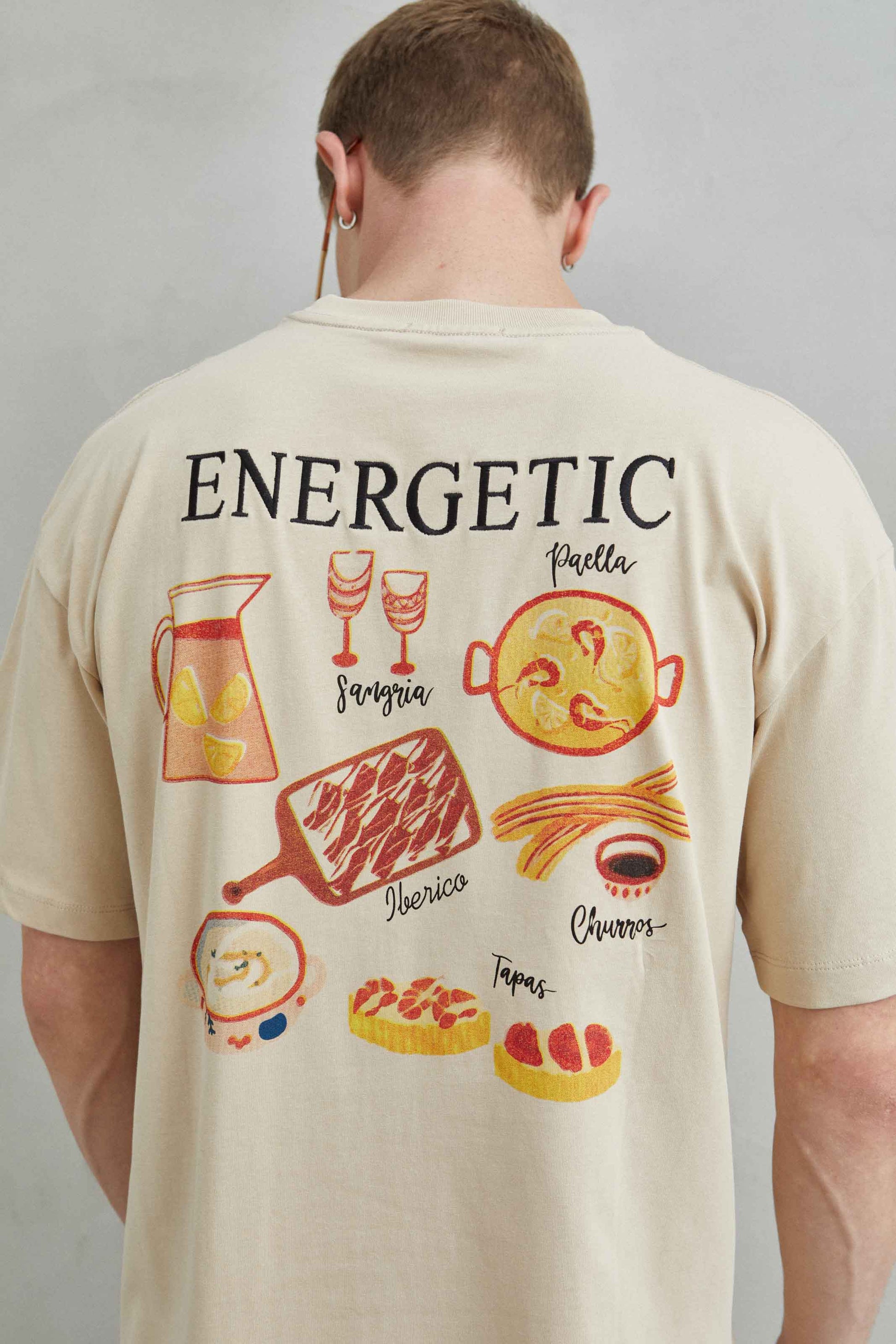 Detalle de la camiseta beige oversize con diseño de comida española, tapas, croquetas y gambas al ajillo
