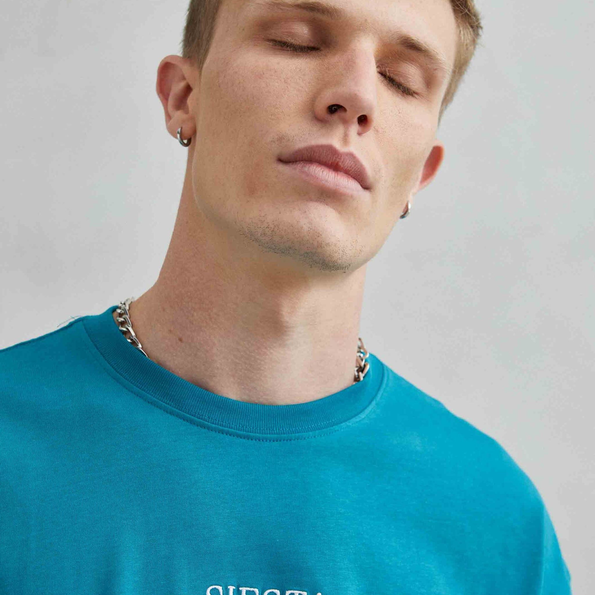 Detalle de camiseta verde oversize con texto bordado "Siesta" y diseño de koala durmiendo