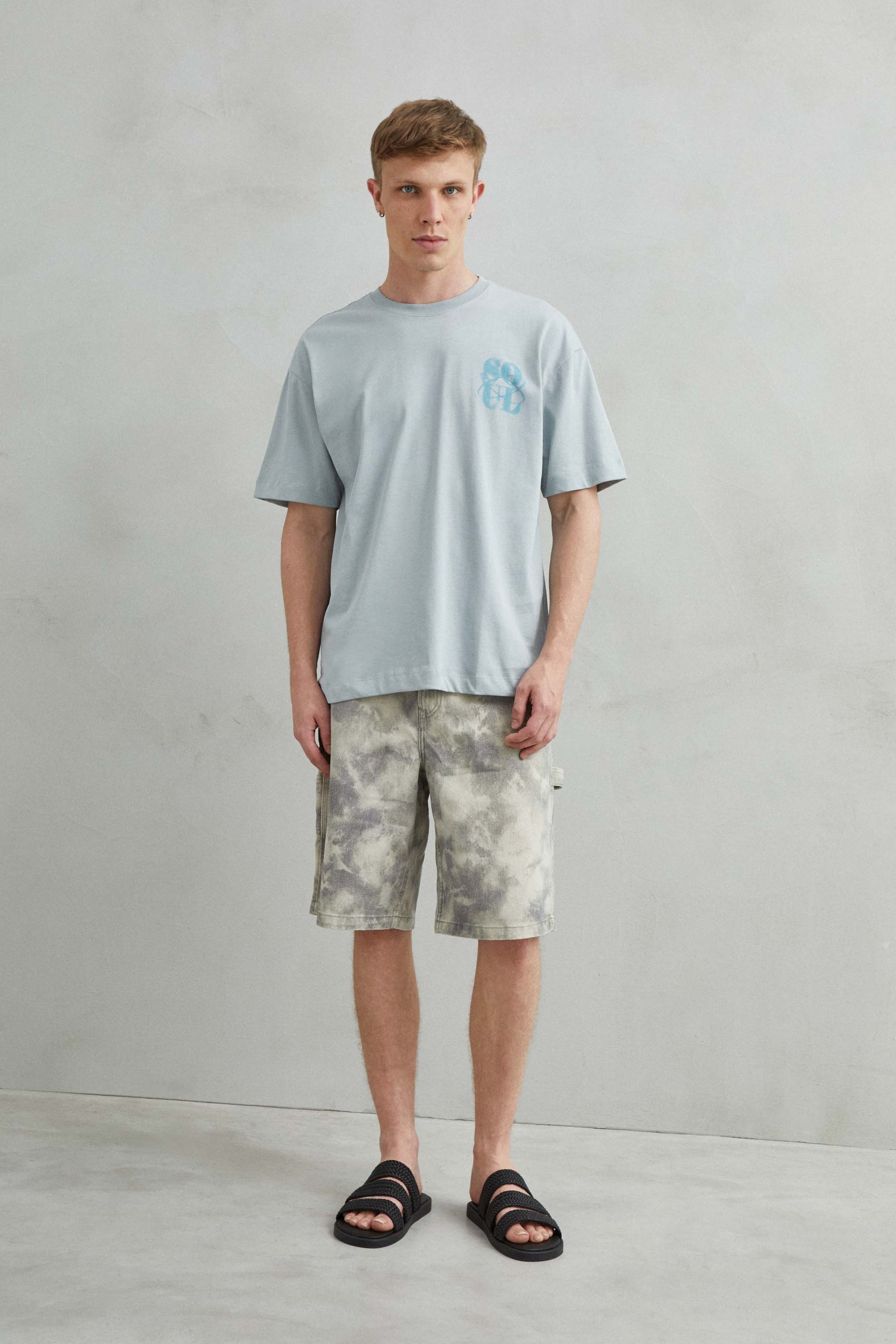 Vista frontal de camiseta gris oversize unisex con diseño abstracto "SOUL" en efecto de arena