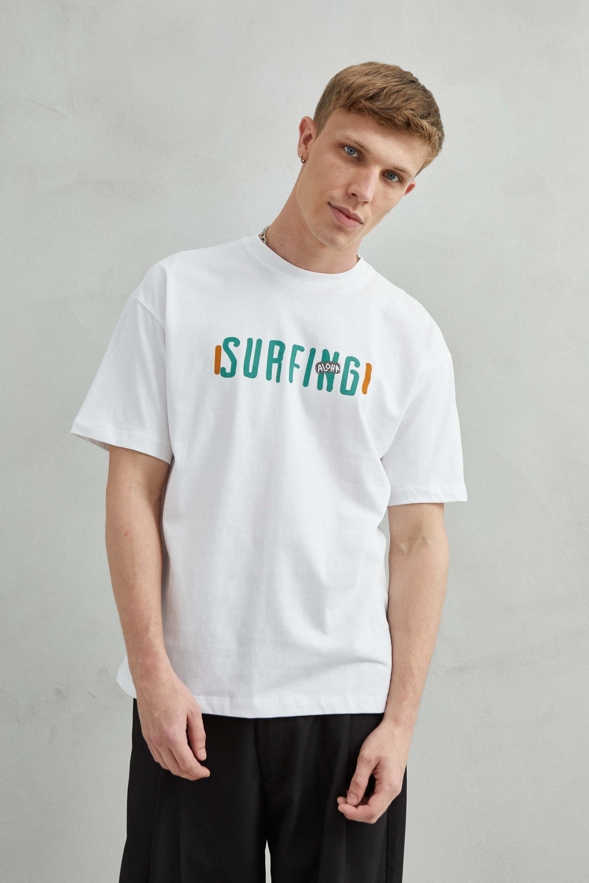  Vista frontal de camiseta blanca oversize unisex con diseño de surf y flores bordadas en la espalda