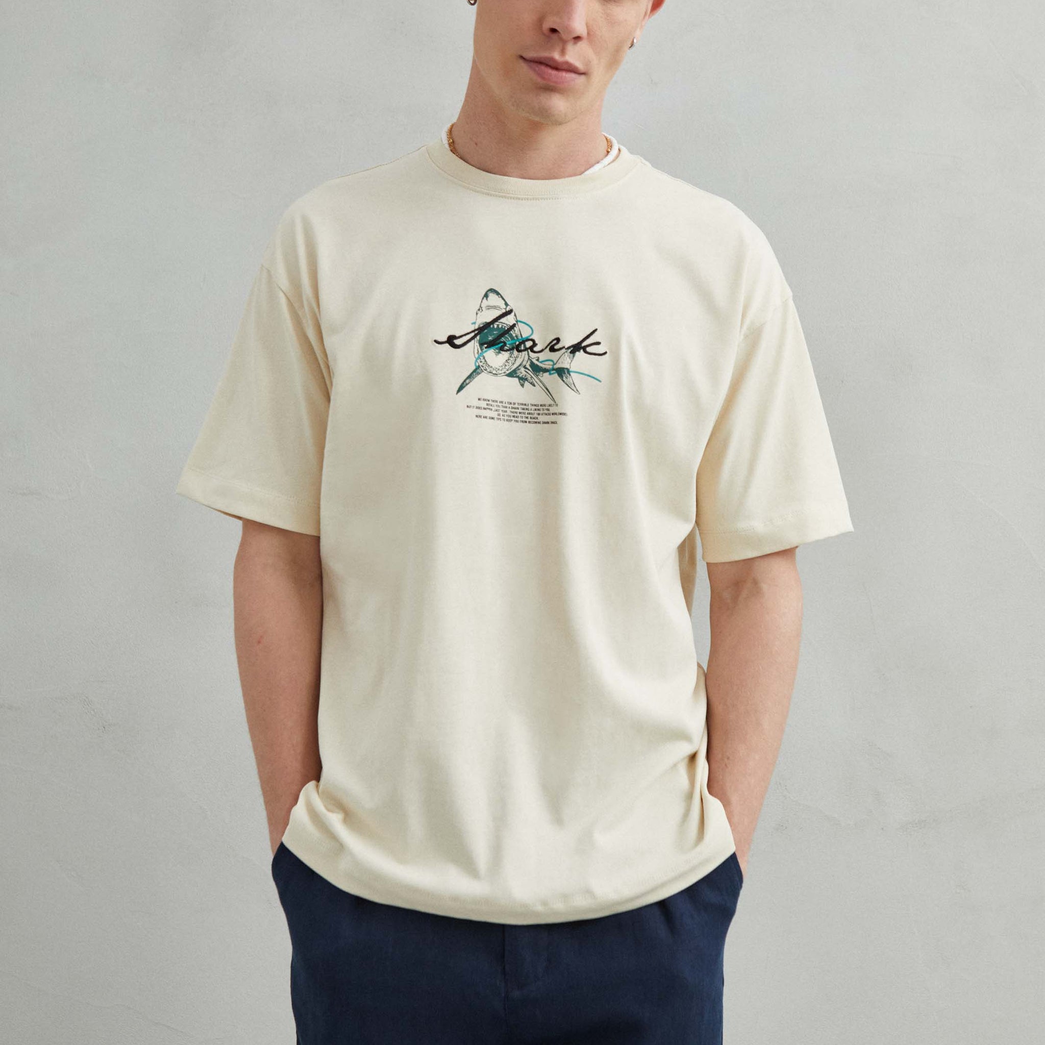 Camiseta beige oversize unisex con diseño "SHARK", tiburón bordado en el frente y gráfico en la espalda