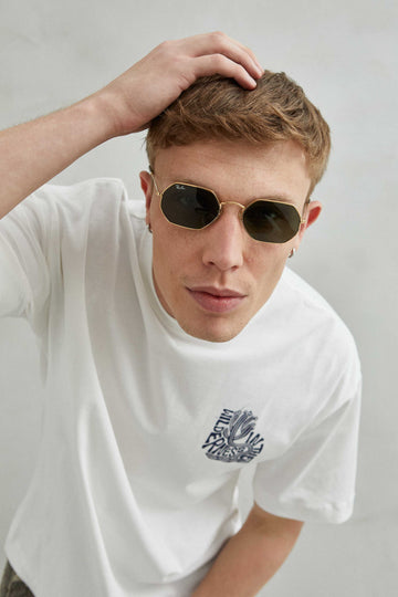 Camiseta blanca oversize unisex con diseño "IN THE WILDERNESS", texto abstracto y cactus curvado con efecto de espuma azul