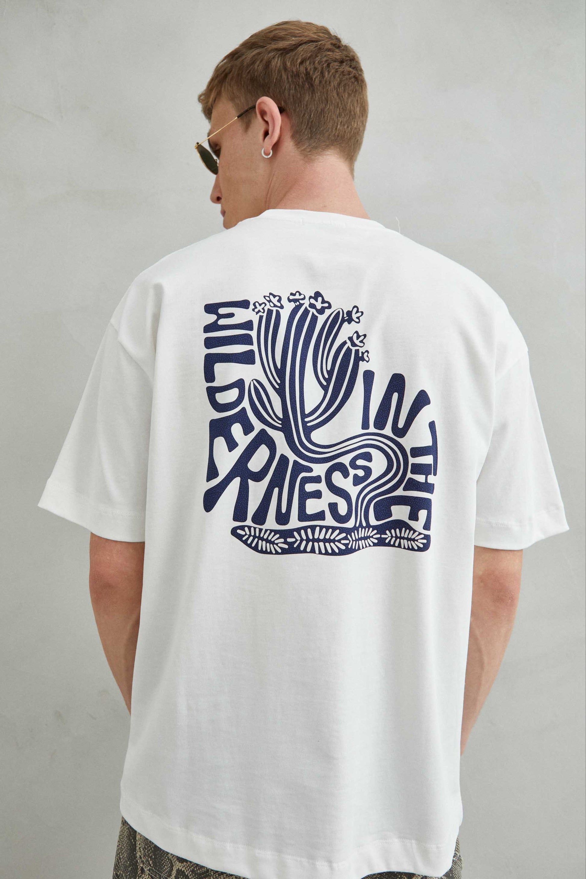 Camiseta 100% algodón con diseño artístico "IN THE WILDERNESS" y cactus curvado en el frente