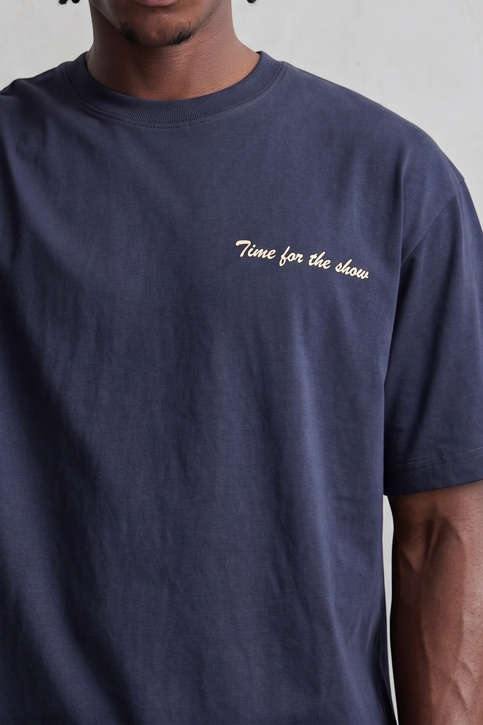 Detalle del texto claro Time for the Show en el pecho de camiseta azul marino.