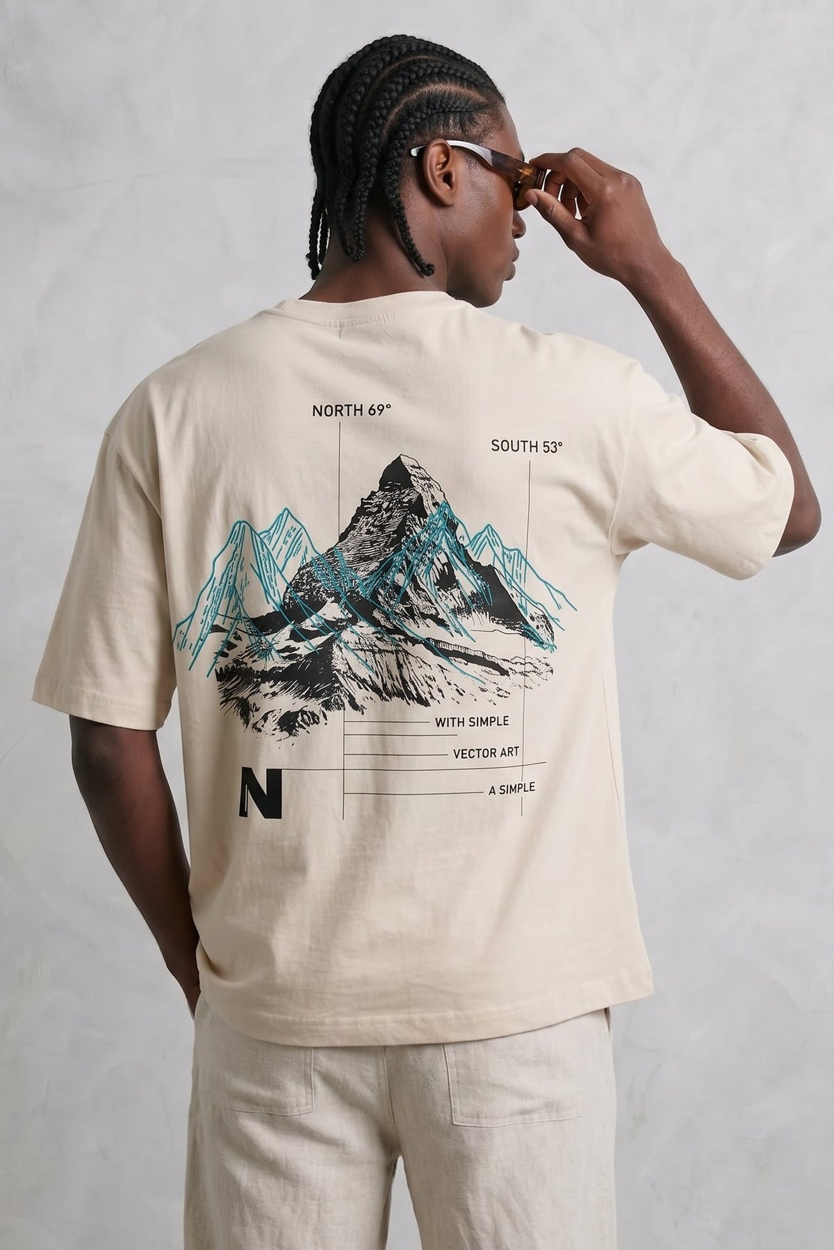 Espalda de camiseta beige Climb High con gran ilustración de montañas en negro y verde azulado.