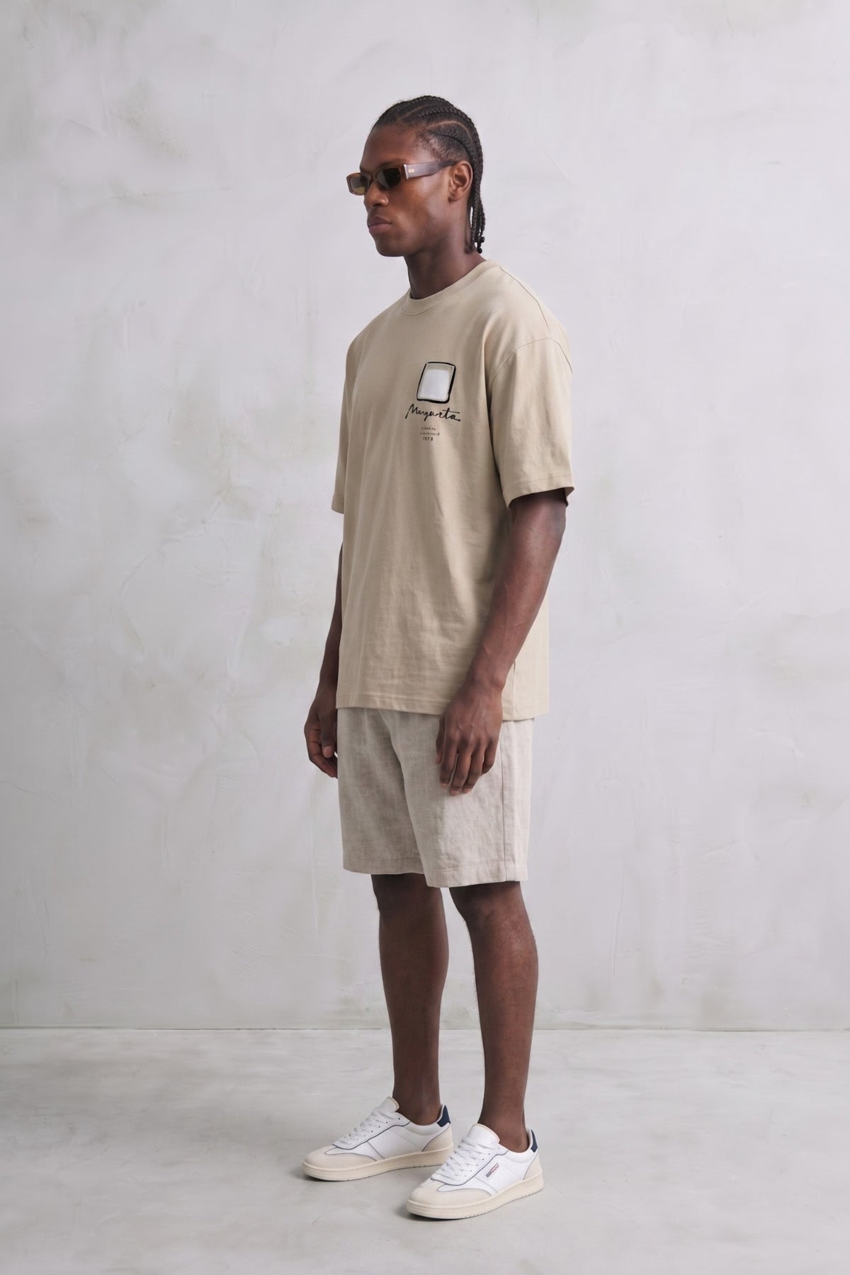 Vista lateral de camiseta oversize beige de cuello redondo y manga corta.