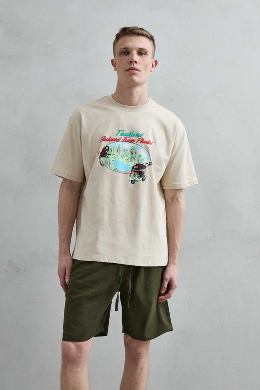 Camiseta oversize beige Thailand Postcard From Phuket con paisaje tropical, mono y tuk tuk, vista frontal.