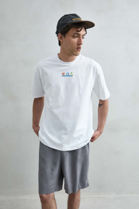 Camiseta oversize blanca con pequeño motivo de cangrejo, scooter y limón en el pecho, vista frontal.
