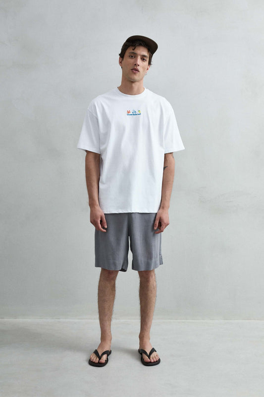 Camiseta oversize blanca con motivo multicolor de cangrejo, scooter y limón, vista de cuerpo entero.
