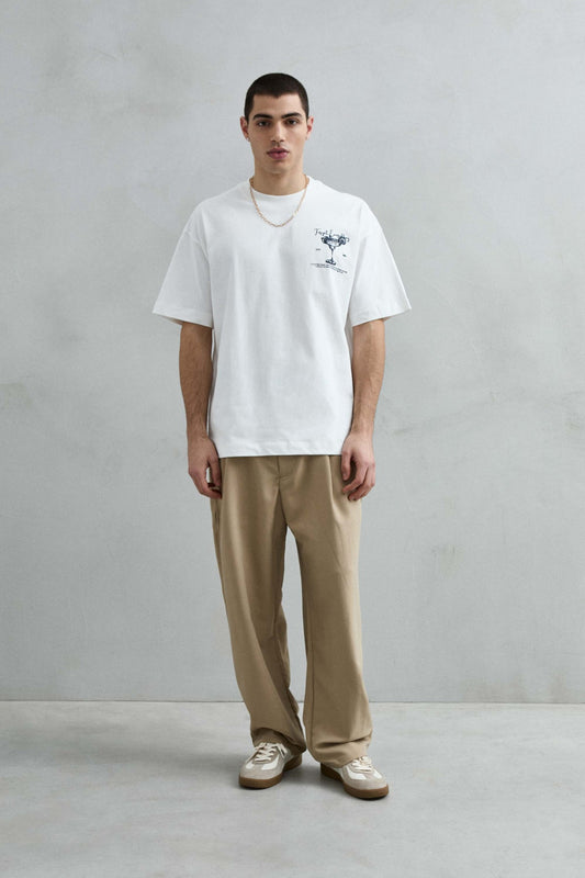 Vista frontal de cuerpo entero de la camiseta oversize blanca Cocktails, con hombros caídos, manga corta amplia y bajo recto.