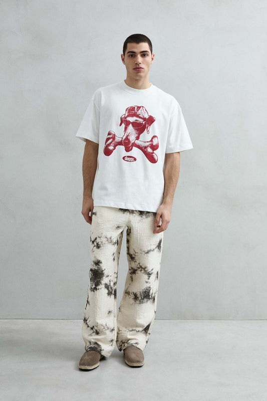Vista frontal de cuerpo entero de la camiseta oversize blanca Doggy, con gran gráfico burdeos de perro y hueso, manga corta amplia y hombros caídos.