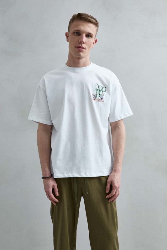Camiseta oversize blanca Feeling Sun con pequeño estampado de cactus verde en el pecho, vista frontal.