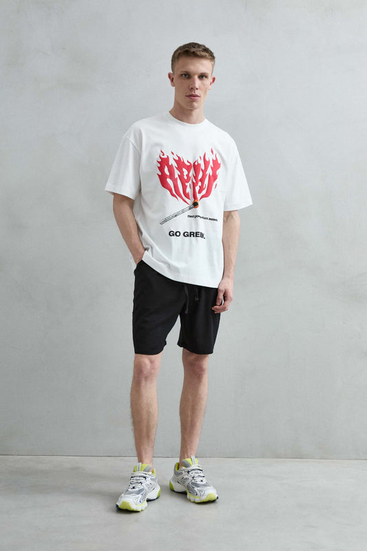 Vista frontal de cuerpo entero de la camiseta oversize blanca Go Greek con estampado de llamas rojas, manga corta amplia y hombros caídos.