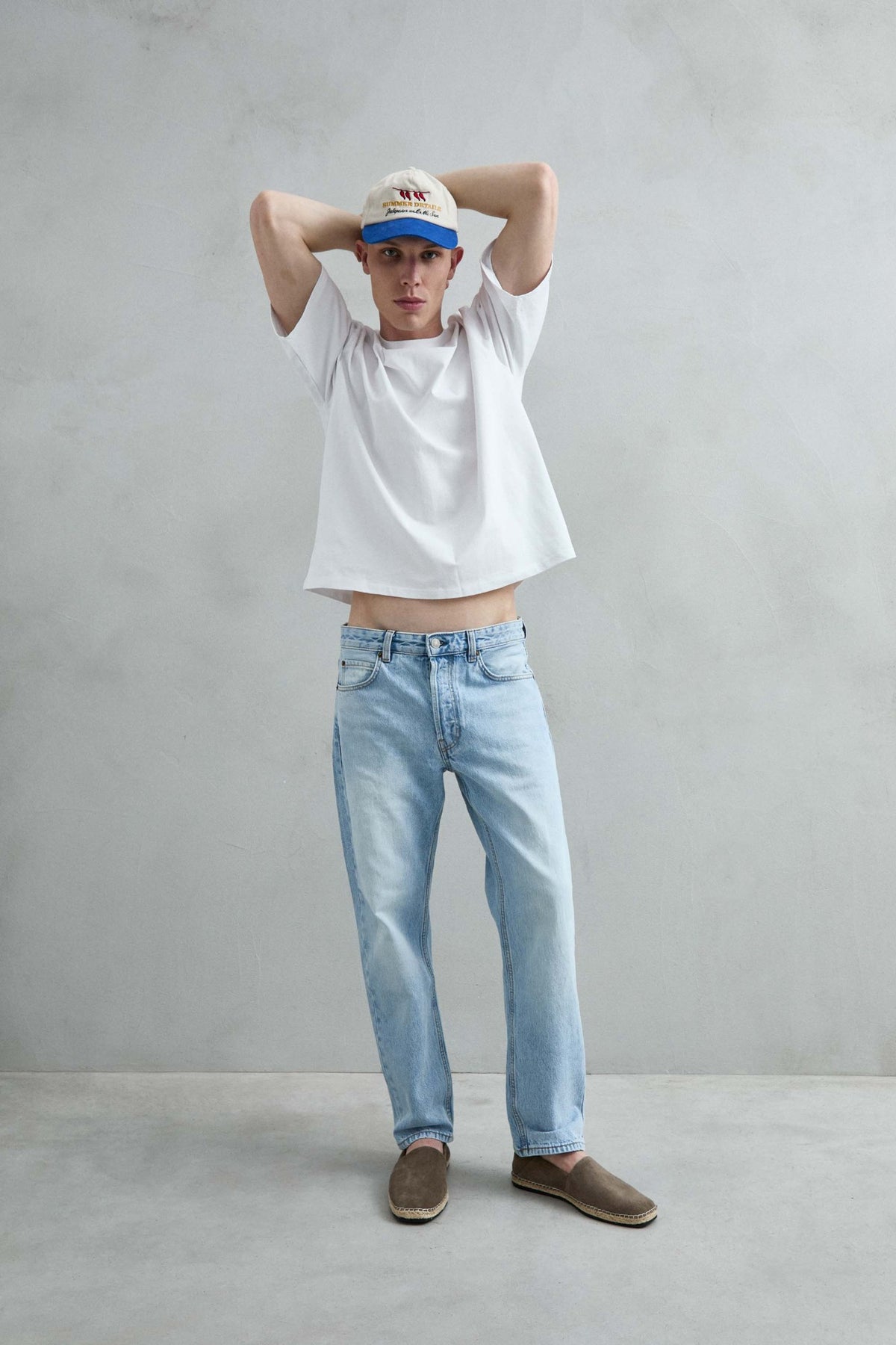 Camiseta oversize blanca lisa con mangas amplias, vista con brazos levantados.