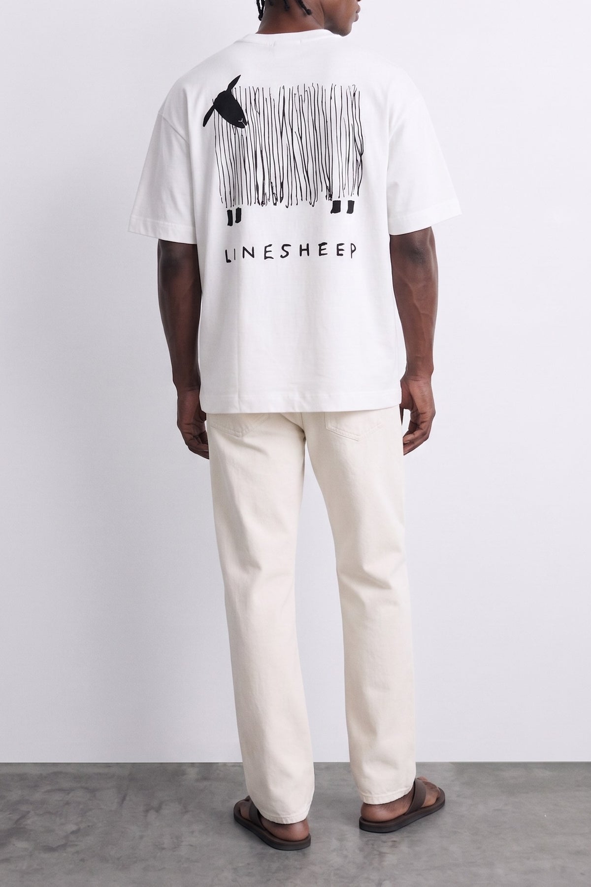 Espalda de camiseta blanca con oveja negra formada por líneas verticales y texto Lone Sheep.
