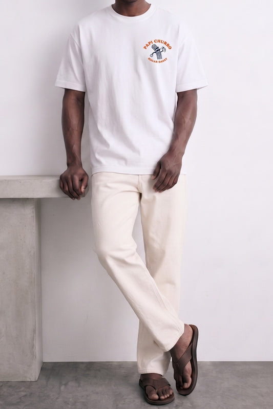 Camiseta oversize blanca Papi Churro, vista de conjunto con el modelo apoyado en una pared.