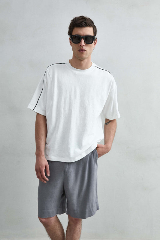 Camiseta oversize blanca con ribete negro en hombros y mangas, vista frontal.