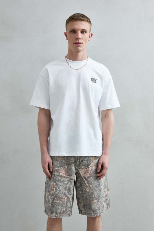Camiseta oversize blanca The Lovers con pequeño motivo de sol en el pecho, vista frontal.