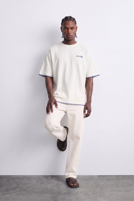 Camiseta oversize crema con costuras azules de contraste, vista de cuerpo entero.