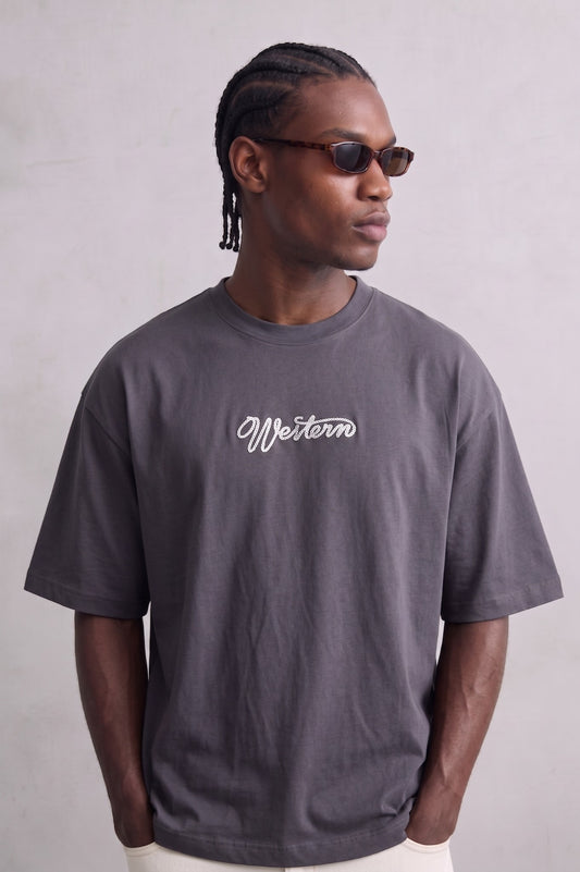 Camiseta oversize gris antracita Western con pequeño texto claro en el pecho, vista frontal.
