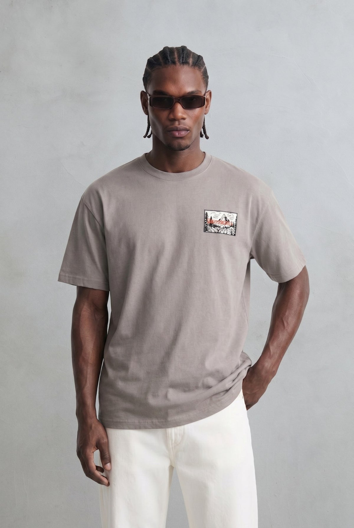 Camiseta oversize color topo con pequeña ilustración rectangular en el pecho, vista frontal.