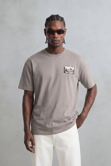 Camiseta oversize color topo con pequeña ilustración rectangular en el pecho, vista frontal.