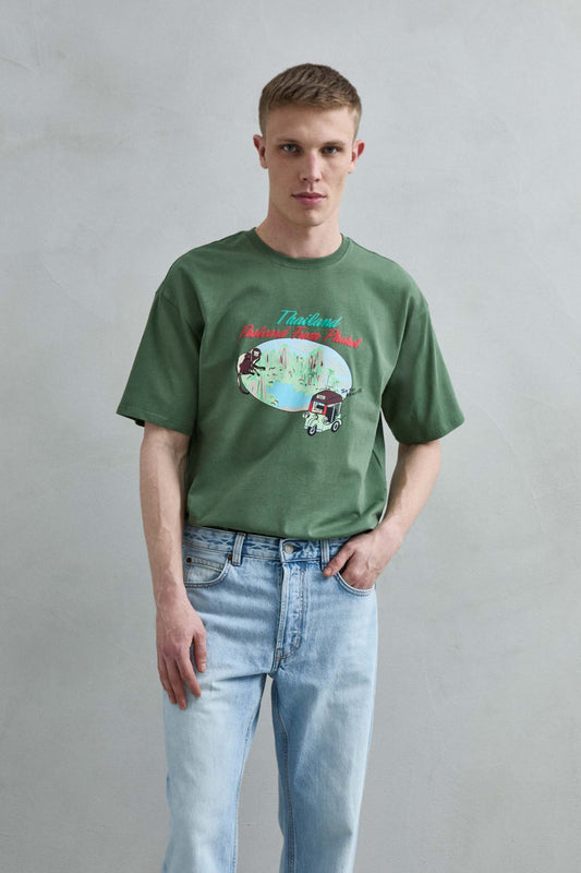 Camiseta oversize verde Thailand Postcard From Phuket con paisaje tropical, mono y tuk tuk, vista frontal.