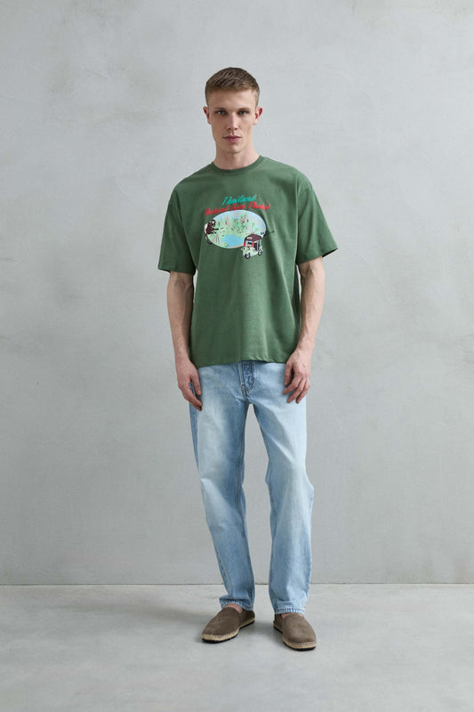 Camiseta oversize verde Thailand Postcard From Phuket con paisaje tropical, mono y tuk tuk, vista de cuerpo entero.