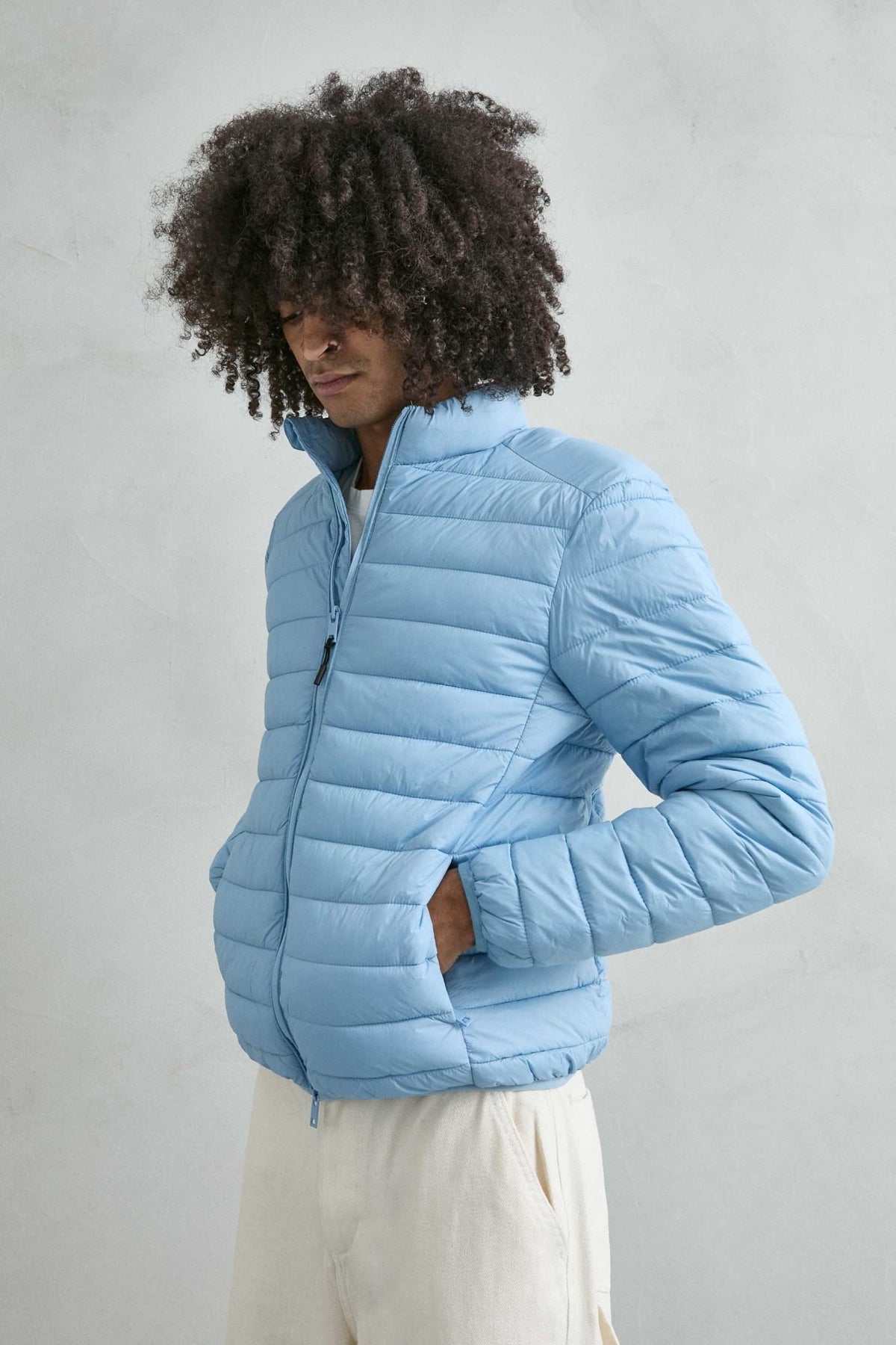 Chaqueta acolchada de hombre azul cielo con cuello alto y cremallera de doble cursor, vista detalle.