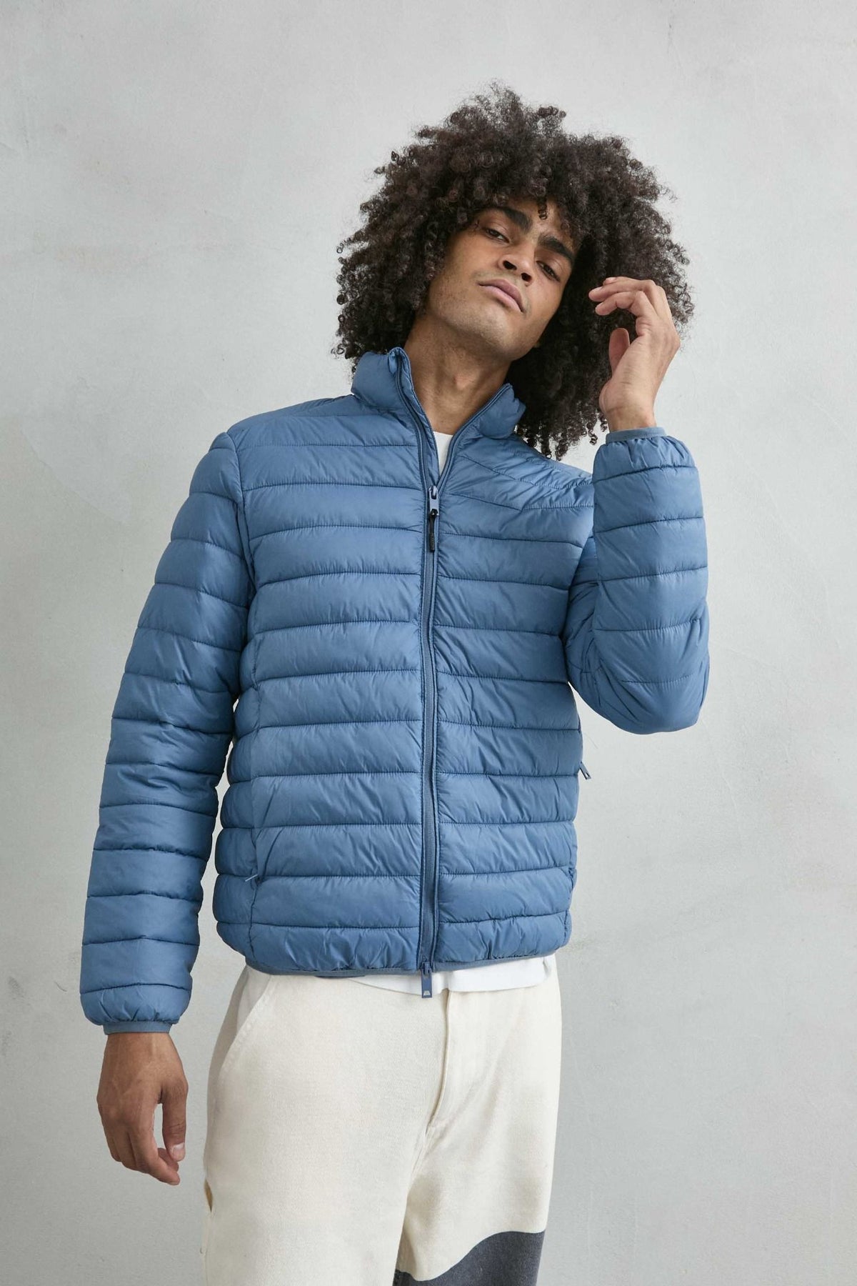 Chaqueta acolchada de hombre azul claro con cuello alto y cremallera de doble cursor, vista detalle.