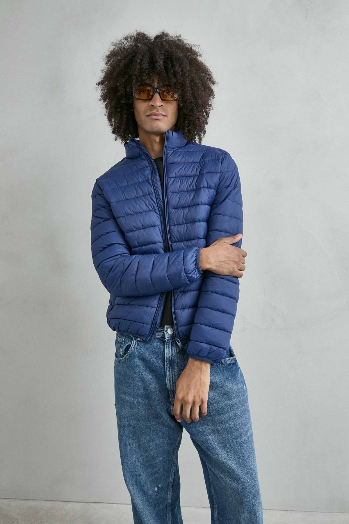 Chaqueta acolchada de hombre azul con cuello alto y cremallera de doble cursor, vista frontal.